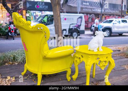 Statuette di bulldog bianco e tavolo giallo d'epoca e poltrona nel parco Foto Stock