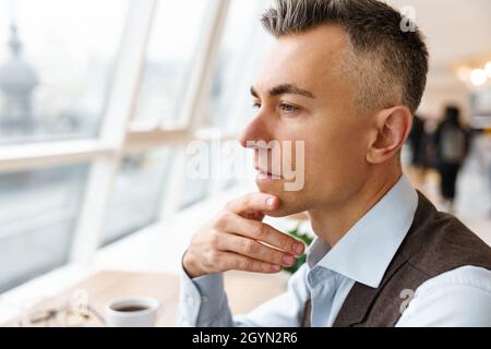 Uomo d'affari fiducioso e pensivo in un caffè al coperto, da vicino Foto Stock