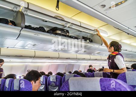 Shanghai Cina, passeggeri cinesi dell'aeroporto di Hongqiao China Air, cabina passeggeri, donna asiatica assistente di volo donna uniforme bagaglio a mano Foto Stock