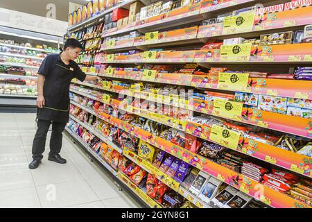 Hong Kong, Wellcome supermercato negozio di alimentari mostra di cibo mercato mercato di vendita caramelle mensole, uomo asiatico uomo maschio dipendente lavoratore di magazzino di lavoro impiegato Foto Stock