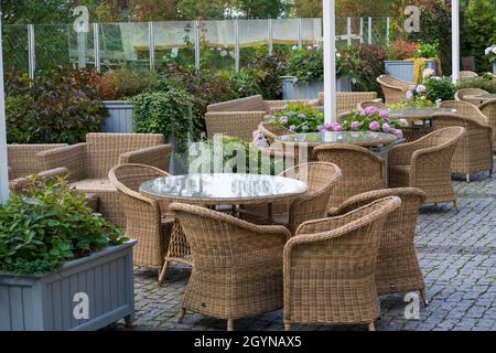 Terrazza vuota all'aperto con mobili in vimini e fiori in vaso per l'intrattenimento estivo Foto Stock