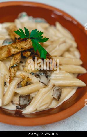 Messa a fuoco superficiale verticale di una deliziosa pasta di pollo Alfredo in una ciotola Foto Stock