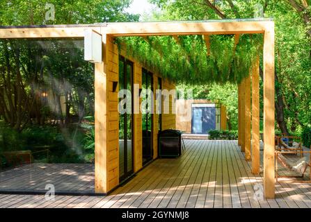 Il tetto è cresciuto con piante verdi, con un bel panorama dell'esterno del caffè nel parco. Moderno design paesaggistico del tetto della casa. Giardino accogliente con legno e v Foto Stock