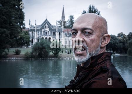 SAN POLO DI PIAVE, ITALY - Jul 17, 2021: Un vampiro maschio spaventoso che sorge vicino ad un castello infestato al Dark Fest di San Polo di Piave, Italia Foto Stock