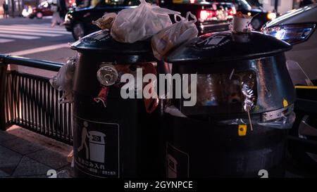 Due bidoni neri pieni di rifiuti sulla strada della città. Mucchio di rifiuti spazzatura sul sentiero. Molti rifiuti di inquinamento e plastica traboccante contenitore e d Foto Stock