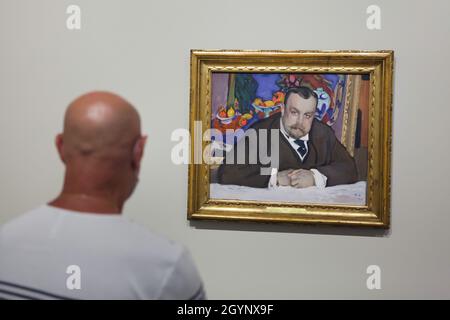 Visitatore di fronte al dipinto a tempera 'Ritratto di Ivan Abramovich Morozov' del pittore impressionista russo Valentin Serov (1909) in mostra alla mostra 'icone di arte moderna dalla collezione Morozov' nella Fondazione Louis Vuitton a Parigi, Francia. Ivan Abramovich Morozov era un collezionista d'arte russo di proprietà di una delle migliori collezioni d'arte modernista francese al mondo. Sullo sfondo del ritratto è raffigurato il dipinto 'frutti e bronzo' del pittore francese Henri Matisse (1910) della sua collezione. La mostra dedicata alla Collezione Morozov è in funzione fino al 22 febbraio 2022. Foto Stock