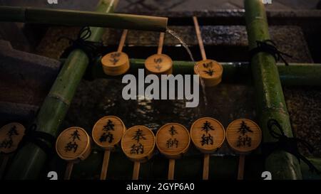 Purificazione a mano lavando alla fontana del santuario di Kyoto. Acqua che corre da bambù canna in Giappone. Ingresso di un tempio giapponese shinto. Foto Stock