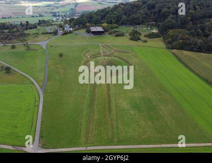 Hessen, Germania. 08 ottobre 2021. 08 ottobre 2021, Hessen, Glauburg: Un tumulo funerario ricostruito, la sezione di una strada processionale e un gruppo di enigmatici pali in legno sono tra le tracce archeologiche del tempo dei Celti oltre 2,400 anni fa che possono essere scoperte sul Glauberg e il suo museo (vista aerea con un drone). Nel 1994, un team di ricerca aveva iniziato gli scavi e scoperto, tra le altre cose, la statua, ormai famosa in tutto il mondo, del "Principe Celtico del Glauberg". L'insediamento celtico nella regione di Wetterau diventerà un sito patrimonio dell'umanità dell'UNESCO. Gli stati federali lo hanno Foto Stock