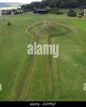 Hessen, Germania. 08 ottobre 2021. 08 ottobre 2021, Hessen, Glauburg: Un tumulo funerario ricostruito, la sezione di una strada processionale e un gruppo di enigmatici pali in legno sono tra le tracce archeologiche del tempo dei Celti oltre 2,400 anni fa che possono essere scoperte sul Glauberg e il suo museo (vista aerea con un drone). Nel 1994, un team di ricerca aveva iniziato gli scavi e scoperto, tra le altre cose, la statua, ormai famosa in tutto il mondo, del "Principe Celtico del Glauberg". L'insediamento celtico nella regione di Wetterau diventerà un sito patrimonio dell'umanità dell'UNESCO. Gli stati federali lo hanno Foto Stock