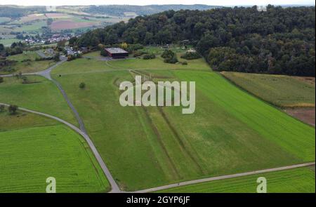 Hessen, Germania. 08 ottobre 2021. 08 ottobre 2021, Hessen, Glauburg: Un tumulo funerario ricostruito, la sezione di una strada processionale e un gruppo di enigmatici pali in legno sono tra le tracce archeologiche del tempo dei Celti oltre 2,400 anni fa che possono essere scoperte sul Glauberg e il suo museo (vista aerea con un drone). Nel 1994, un team di ricerca aveva iniziato gli scavi e scoperto, tra le altre cose, la statua, ormai famosa in tutto il mondo, del "Principe Celtico del Glauberg". L'insediamento celtico nella regione di Wetterau diventerà un sito patrimonio dell'umanità dell'UNESCO. Gli stati federali lo hanno Foto Stock