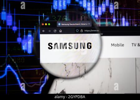 Samsung Company logo su un sito web con blurry mercato azionario sviluppi in background, visto su uno schermo di computer attraverso una lente d'ingrandimento Foto Stock