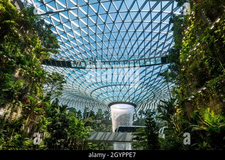 Insside la cupola all'Aeroporto di Chang, Singapore con il treno che passa con un cielo blu. Foto Stock