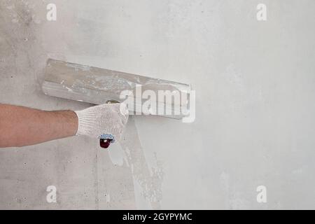 La mano di artigiano maschile in guanto contiene la cazzuola da costruzione Foto Stock