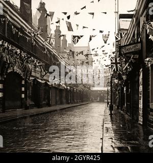 Gli Shambles a Huddersfield, Yorkshire, Inghilterra nel 1937. Le indicazioni per "Tripe Taylor's Stall" e "Fish Chips Pies Peas" (a destra) sono tipiche delle strade della città di mercato inglese negli anni '1930 Bandiere, grappoli e striscioni celebrano l'incoronazione del monarca britannico, re Giorgio vi. Foto d'epoca da collezione privata. Foto Stock