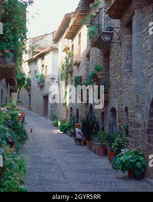 CALLE EMPEDRADA TIPICA-SEÑORA SENTADA A LA PUERTA DE SU CASA. Ubicazione: ESTERNO. Ainsa. HUESCA. SPAGNA. Foto Stock