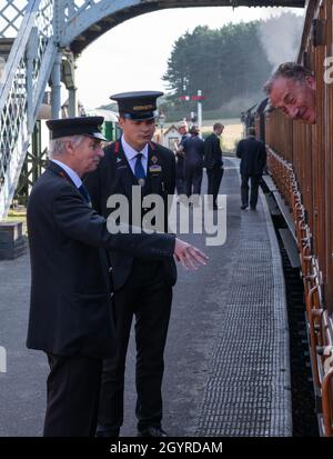 Sheringham, Norfolk, Regno Unito - SETTEMBRE 14 2019: Uomo e adolescente negli anni '40 le uniformi del conduttore di treno parlano all'uomo su un LNER Quad Art Set 1924 48661-4 vinta Foto Stock