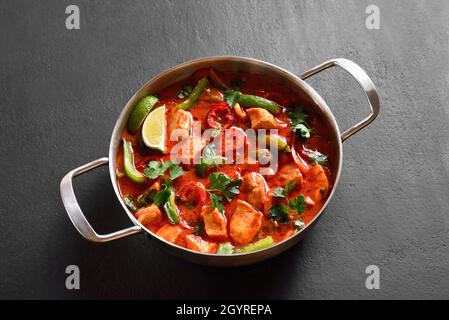 Curry di pollo rosso di stile thailandese con verdure in padella su sfondo di pietra nera. Vista ravvicinata Foto Stock