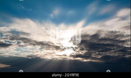 Raggi del sole che si infrangono attraverso le nuvole scure. Solo cielo, nessuna terra. Foto Stock