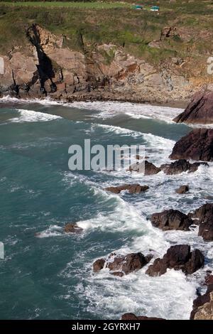 Il surf scorre nella Caerfai Bay sotto le scogliere sul sentiero costiero del Pembrokeshire, Galles, Regno Unito Foto Stock