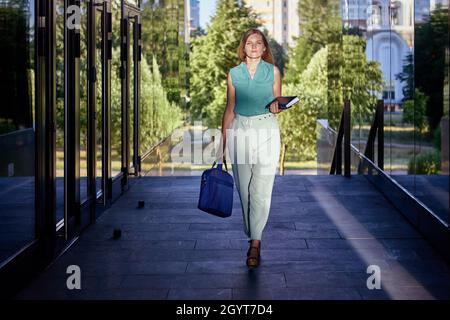 Il collare bianco cammina vicino al centro affari con borsa per lavoro. Foto Stock