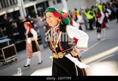 Stoccarda, Germania. 9 ottobre 2021. Per celebrare il 200° anniversario della Rivoluzione greca nel 1821, le donne in abito tradizionale camminano in una parata commemorativa e onoraria, allietata da decine di spettatori. Credit: Christoph Schmidt/dpa/Alamy Live News Foto Stock