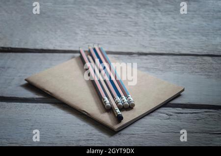 Concetto di una matita con un unico strumento gomma nera collocata su un marrone note book e collocato sul tavolo di legno in stile vintage Foto Stock