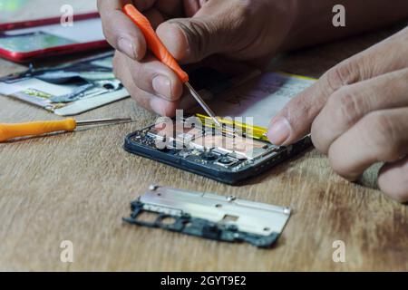 Riparazione di parti della scheda madre del telefono nella scheda madre per smartphone da parte di un tecnico professionista su un tavolo. Foto Stock