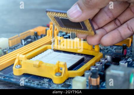 Mano del tecnico che tiene la CPU o l'unità centrale di elaborazione chip microprocessore di fissaggio e aggiornare il computer pc per la riparazione all'interno della scheda madre socket Foto Stock