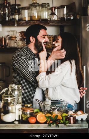 Giovane coppia felice con farina sulle facce che forno torta di agrumi Foto Stock