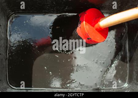 Pennello in vernice nera. Spazzolare in un contenitore con vernice impermeabile. Uno strumento per la colorazione della superficie. Vernice spessa in un vaso. Foto Stock