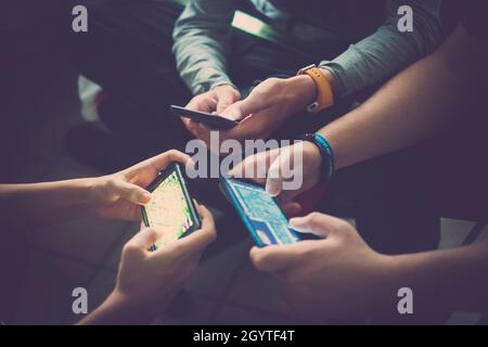 Primo piano delle mani di tre giovani amici dipendenti dalla tecnologia che giocano insieme con gli smartphone. Ragazzi adolescenti che usano i telefoni cellulari per la rete sociale Foto Stock