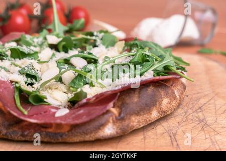 Primo piano di una pizza con prosciutto crudo, parmigiano, mandorle e razzo. Foto Stock