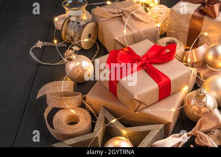Regali e decorazioni natalizie illuminate da una ghirlanda su sfondo scuro. Vista laterale, spazio di copia. Foto Stock