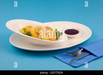 Una porzione di tre pancake rotondi di formaggio cagliato su un piatto bianco. Colazione sana. Sfondo blu. Spazio di copia. Foto Stock