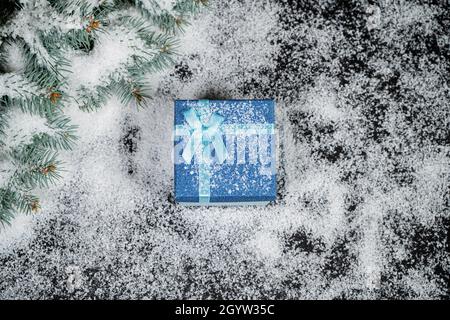 Regalo decorativo di Natale rosso nella neve d'inverno con un'etichetta vuota per il vostro saluto stagionale. Foto Stock