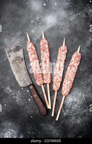 Kebab di carne crudo kofta insaccati set, su sfondo nero tavolo di pietra scura, vista dall'alto piatto Foto Stock