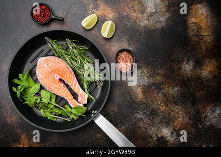 Bistecca di salmone fresco crudo, in padella in ghisa, su vecchio sfondo rustico scuro tavolo, vista dall'alto piatto, con spazio per la copia del testo Foto Stock