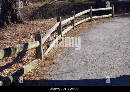 Una vecchia recinzione in legno spaccato ferrovia lungo un sentiero escursionistico in un parco Foto Stock