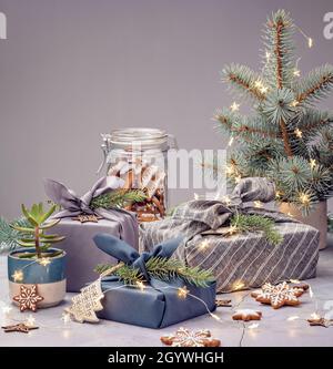 Zero rifiuti di Natale riciclaggio, riutilizzo, stile di vita sostenibile concetto. Confezione regalo ecologica in stile furoshiki, piante e biscotti fatti in casa. Foto Stock