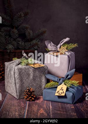 Tre scatole regalo ecologico in stile furoshiki su sfondo scuro. Zero rifiuti di Natale riciclaggio, riutilizzo, stile di vita sostenibile concetto. Foto Stock