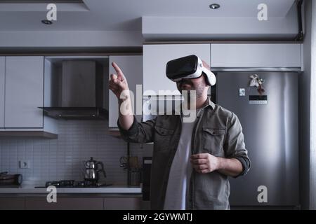 uomo che indossa occhiali per realtà virtuale aumentata in cucina Foto Stock