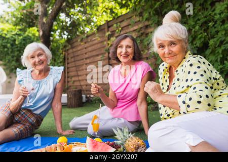 Belle donne anziane rilassarsi a casa nel giardino - tre belle donne mature riposo in un giardino tranquillo cortile Foto Stock