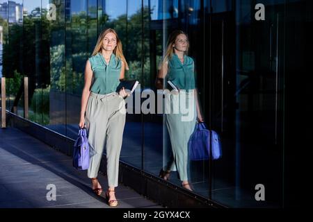 Il segretario in tuta d'affari cammina vicino al centro degli uffici. Foto Stock