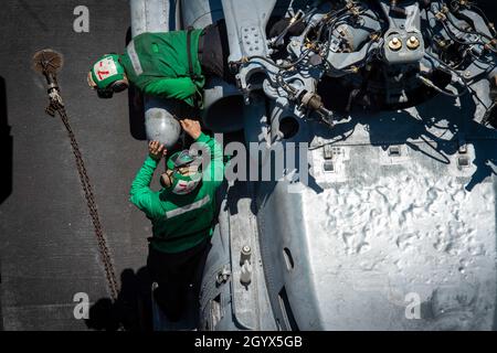 211008-N-RB149-1148 SOUTH CHINA SEA (OTT 8, 2021) i marinai, assegnati allo "Blue Hawks" Maritime Strike Squadron (HSM) 78, eseguono la manutenzione preventiva su un MH-60R Seahawk sul ponte di volo della portaerei di classe Nimitz USS Carl Vinson (CVN 70), 8 ottobre 2021. Carl Vinson Carrier Strike Group è in fase di implementazione nell'area operativa della 7a flotta statunitense per migliorare l'interoperabilità attraverso alleanze e partnership, fungendo da forza di risposta pronta a supportare una regione indopacifica libera e aperta. (STATI UNITI Foto Navy di Mass Communication Specialist 3a Classe Nicholas Cart Foto Stock