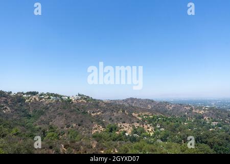 Vista delle colline di Hollywood vista da Mulholland Drive in una soleggiata giornata estiva. Case, alberi e zone asciutte di terra che si estendono attraverso la valle Foto Stock