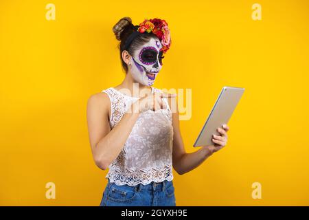 Catrina messicana, ritratto di giovane donna latina con tavoletta digitale, festa di Halloween in Messico Foto Stock