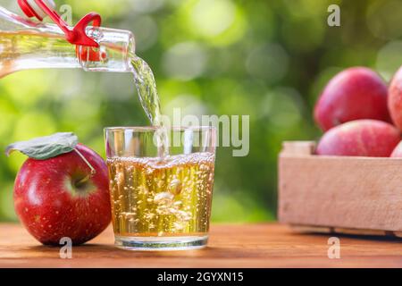 sidro di mele o succo versando in vetro dal flacone Foto Stock
