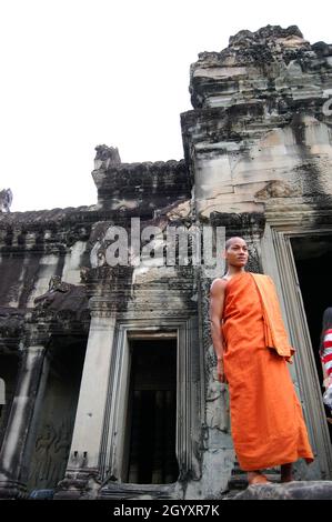 Cambogiano monaco novizio viaggio Visita e stand meditazione rituale rispetto pregare in antiche rovine antico edificio castello Khmer Impero di Angkor Wat cit Foto Stock