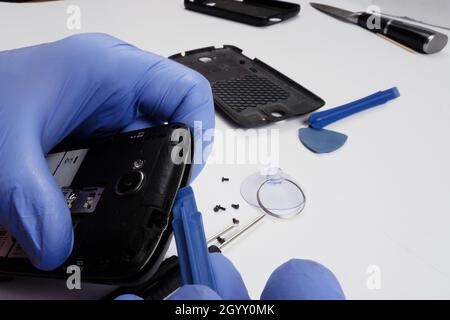 il master ripara uno smartphone rotto con l'aiuto di strumenti. Foto Stock