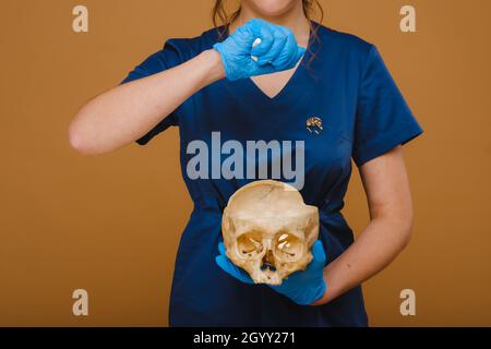 Un medico piuttosto giovane versa le capsule di vitamina in un cranio umano. Il medico versa le pillole sullo sfondo Foto Stock